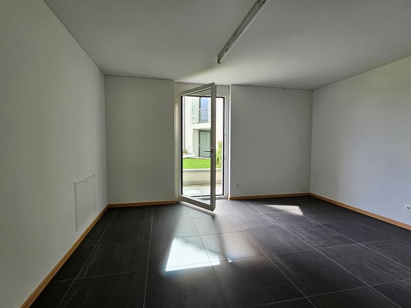 Empty room, black tiled floor, open door to balcony, neutral white walls