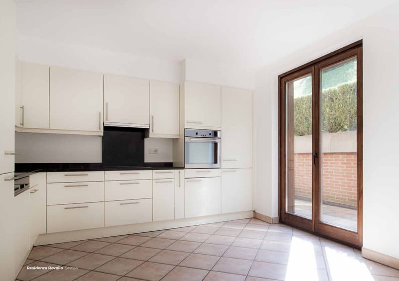 white kitchen cabinets, stainless steel oven, tile floor, sliding doors to balcony, brick wall outside