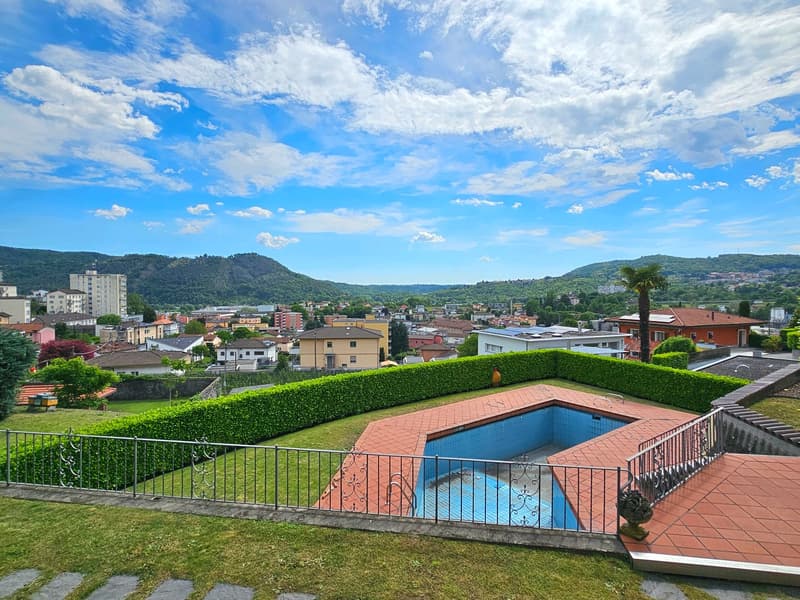 Garden with a swimming pool, hedge, pool fence, mountain range view, blue sky, city view