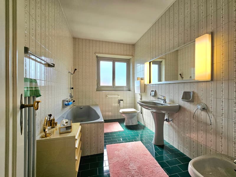 Bathroom with bathtub, toilet, sink, mirror, towel rack, and green tiles