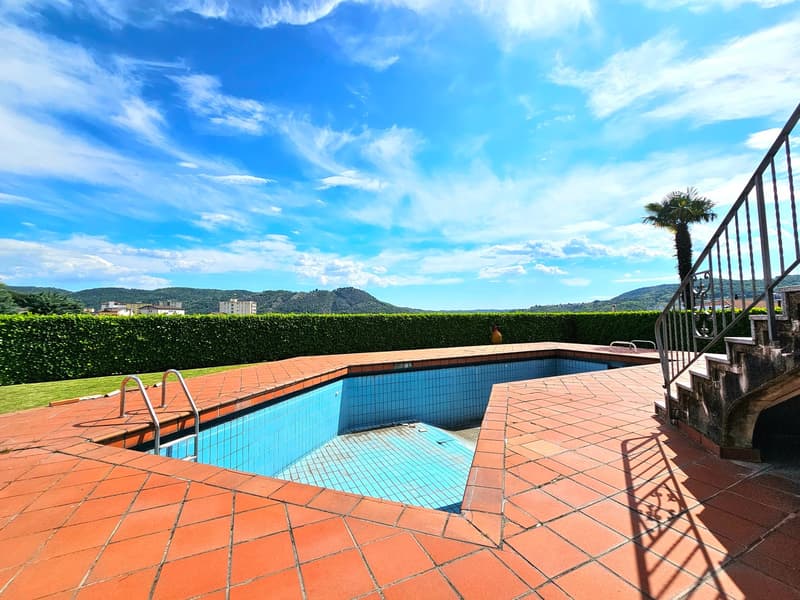 Swimming pool, red tile floor, green bush, handrail, staircase