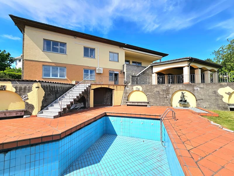 Detached house with swimming pool, large building with multiple windows, stairs leading to the entrance, red tiles surrounding the pool