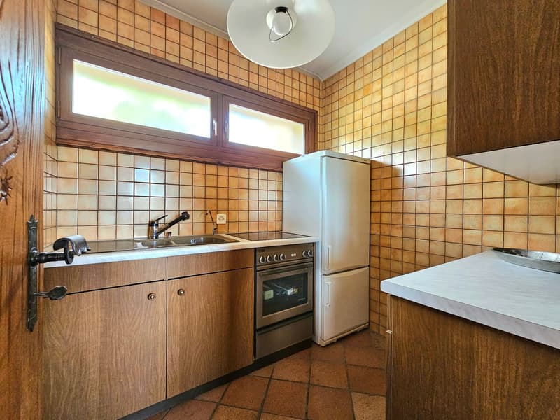 vintage style kitchen with tiled walls, built-in appliances, wooden cabinets, stainless steel sink and faucet