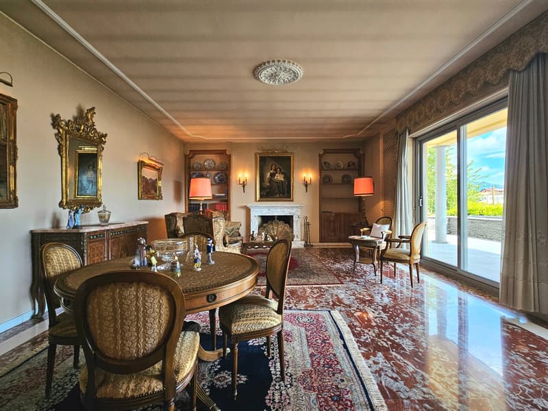 elegant chandelier, marble flooring, dining table, upholstered chairs, fireplace, lamps, sideboard, decorative items, framed pictures, open sliding doors to terrace