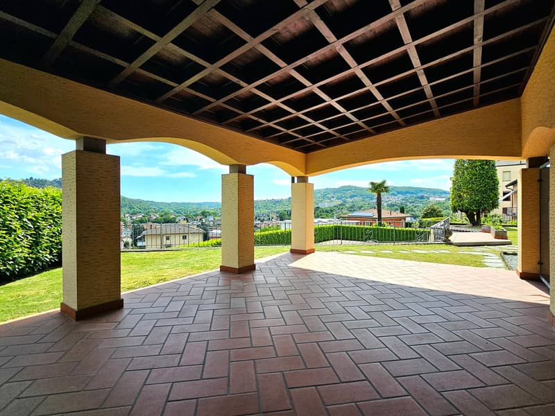 Terrace with a stone floor, covered by a wooden ceiling with an open view towards the landscape.