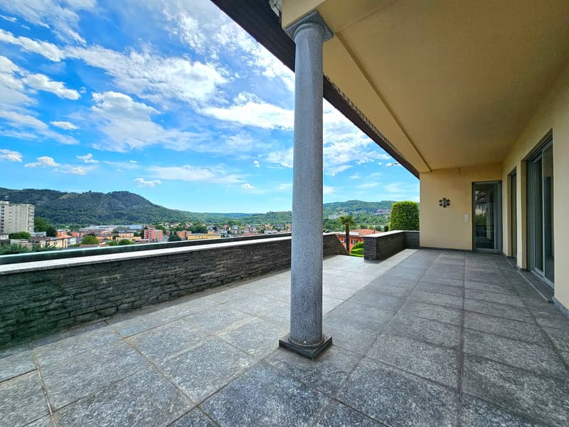 Terrace with stone pillar, grey tiled floor, overlooking cityscape, mountains in distance