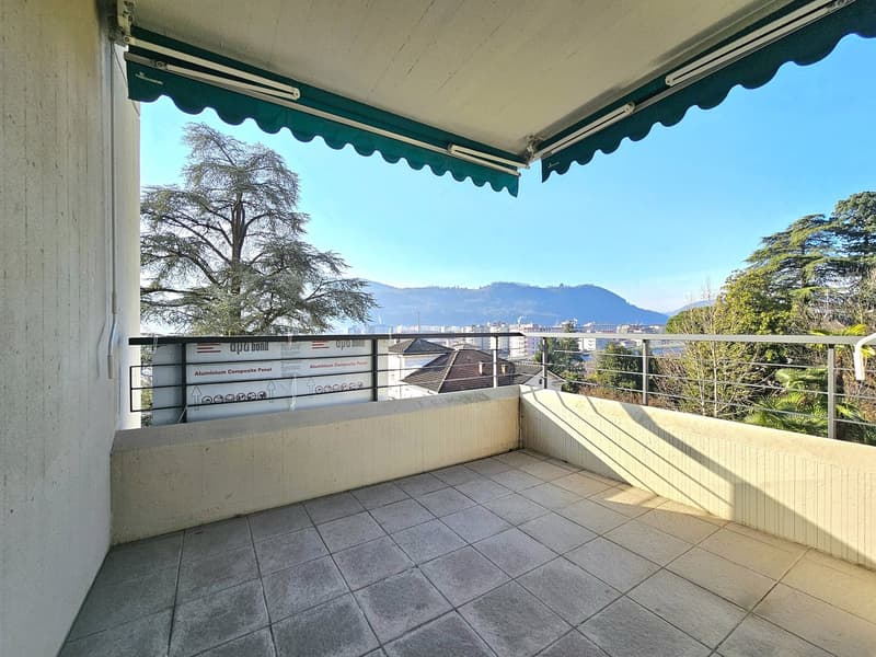 tiled balcony with metal railings, trees and mountains in the background