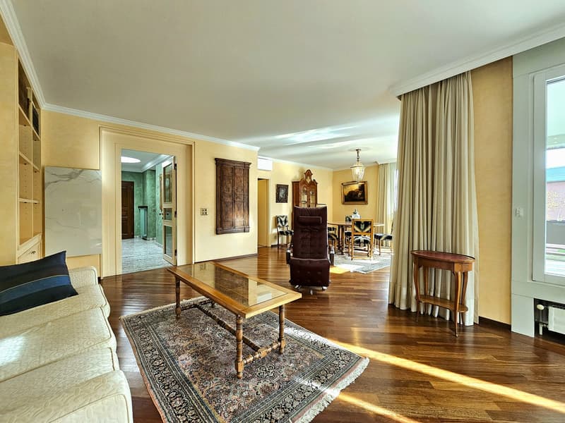 large open space, hardwood floors, chandelier, sofa, coffee table, armchair, wooden desk, dining area with chairs and table