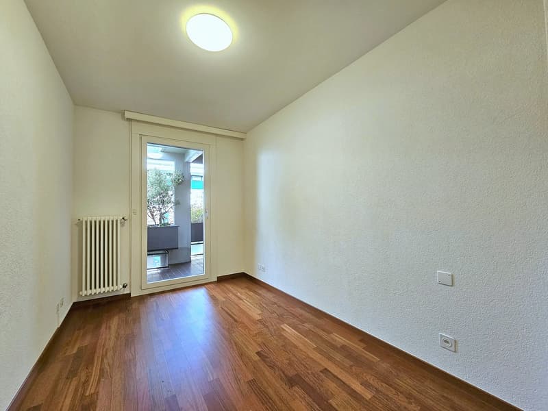 empty room, white walls, wooden floor, sliding glass door, ceiling light, radiator