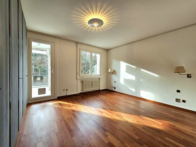 hardwood floor, large glass doors leading to balcony, large windows, ceiling lamp, wall lamps