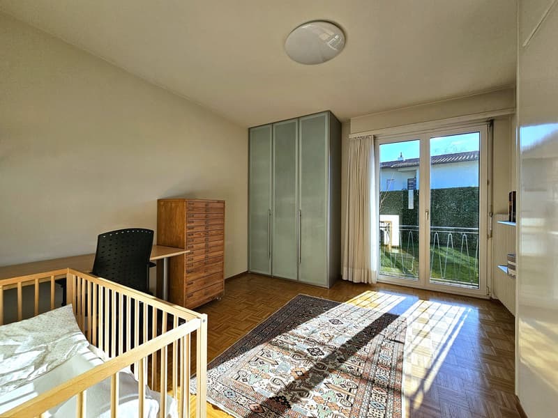wooden crib, desk, black chair, wooden dresser, wooden wardrobe, carpet, sliding glass doors, balcony