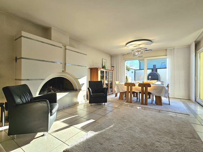 white walls, arched fireplace, black armchairs, white rug, dining table with chairs, glass door leading to the balcony, chandelier