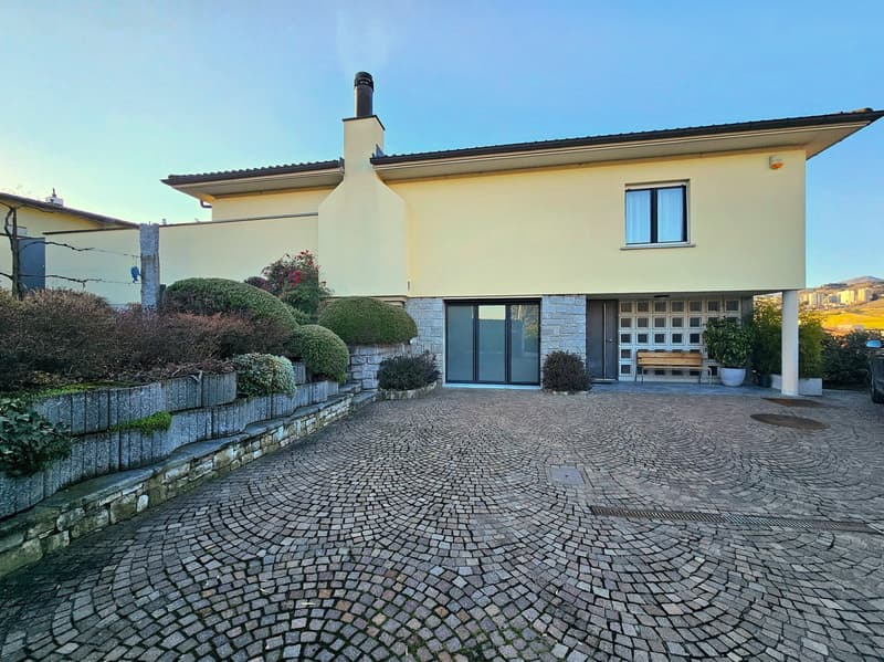 two-story house, yellow exterior, brick and white pillars, large windows, brick driveway