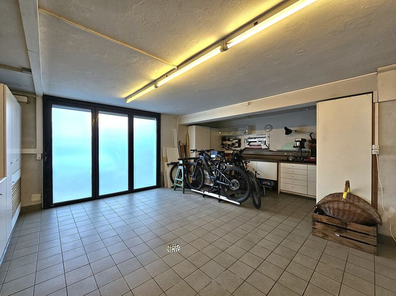 empty room with tiled floor, windows, bikes, cabinets, desk, clock