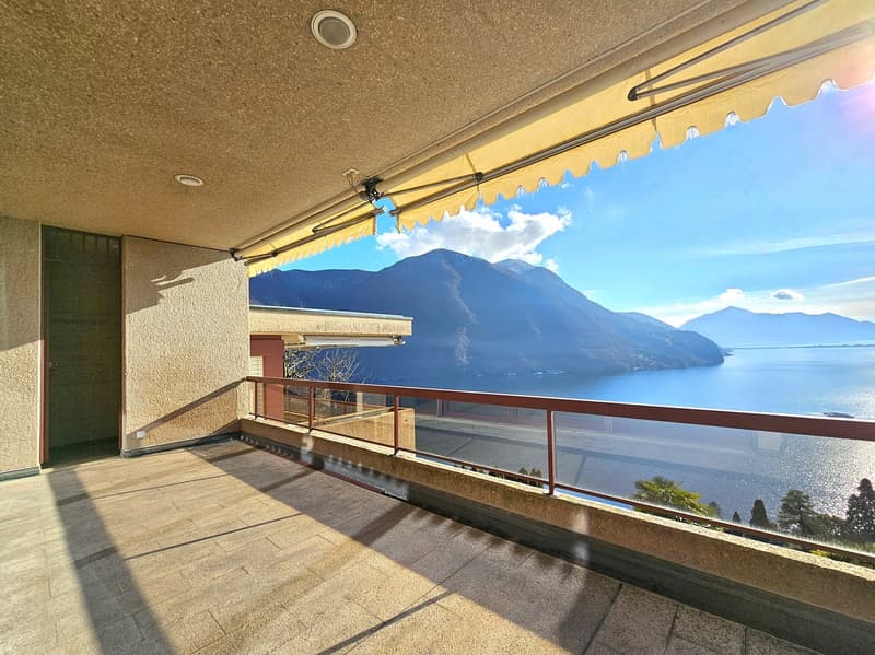 Balcony with tiled floor, metal railing, retractable canopy, and a stunning view of mountains and lake