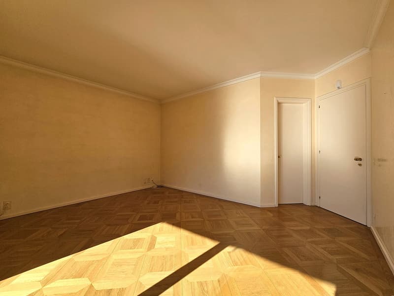 empty room with hardwood floors, walls painted in a warm beige color, power outlets on the walls, doors with gold handles