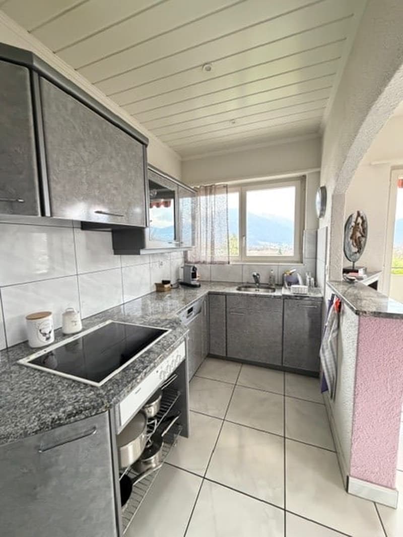 Modern kitchen with granite countertops, stainless steel appliances, and gray cabinets.