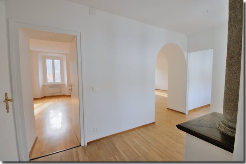 white walls, wooden floor, arched window, white doors
