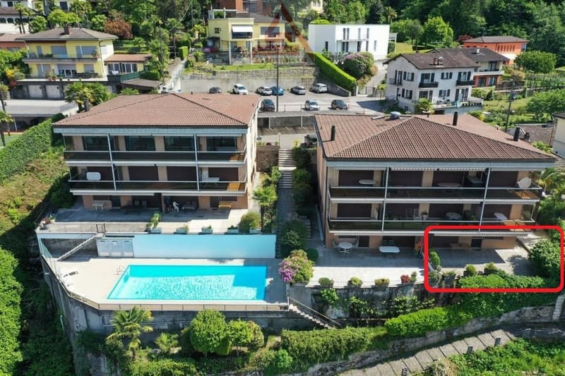 Multi-story apartment building with a swimming pool, surrounded by lush greenery and other residential buildings