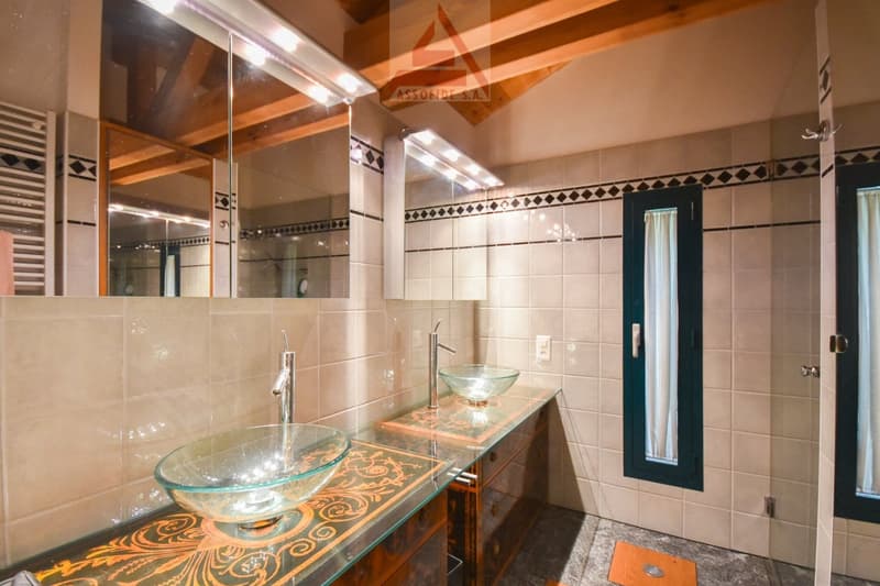 Large bathroom with wooden vanity, glass vessel sinks, patterned tile walls, and recessed lighting.