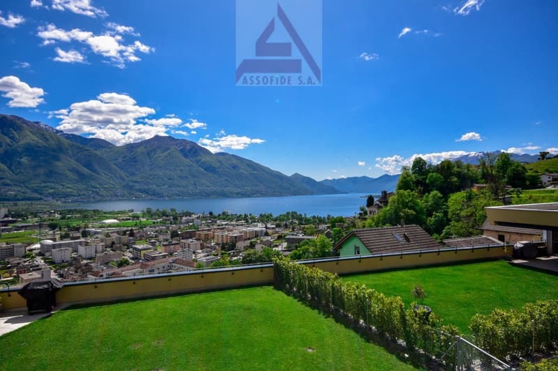Green grass lawn, fenced, grassy areas, trees, city, mountain, water, houses, and clear blue sky