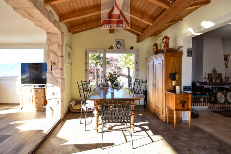 dining room with large windows, wooden dining table, chairs, wooden cabinet, TV, flower vase, wooden flooring