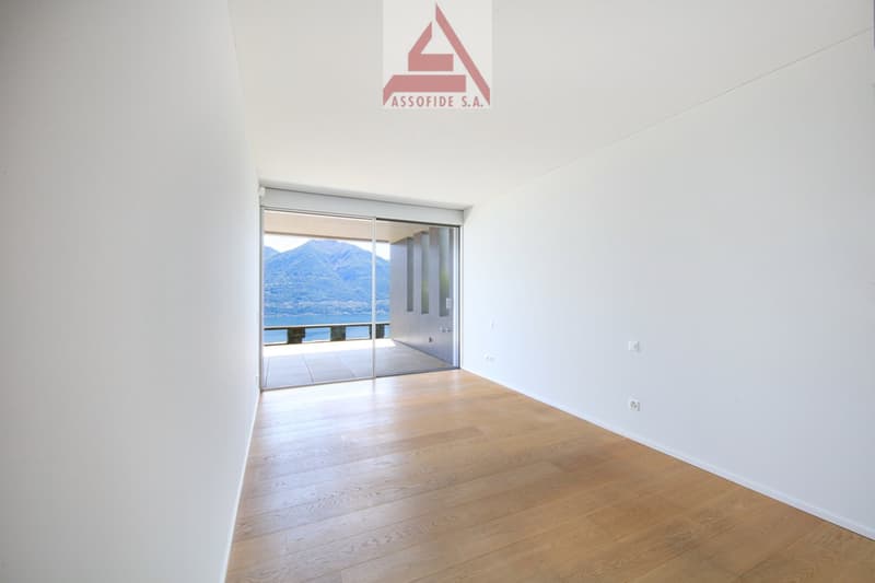 Empty room, wooden floor, sliding glass doors, view of a lake and mountains