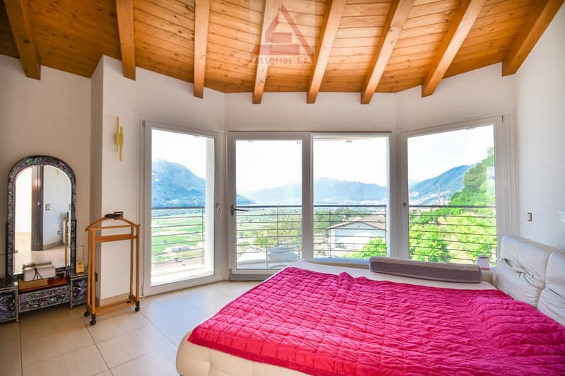 bedroom with large windows and a balcony, wooden ceiling, pink bedspread, white walls, glass mirror