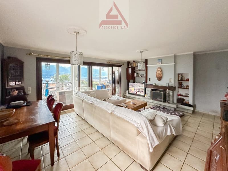 living room with sofa, coffee table, TV, fireplace, dining table, chairs, glass doors, lake view