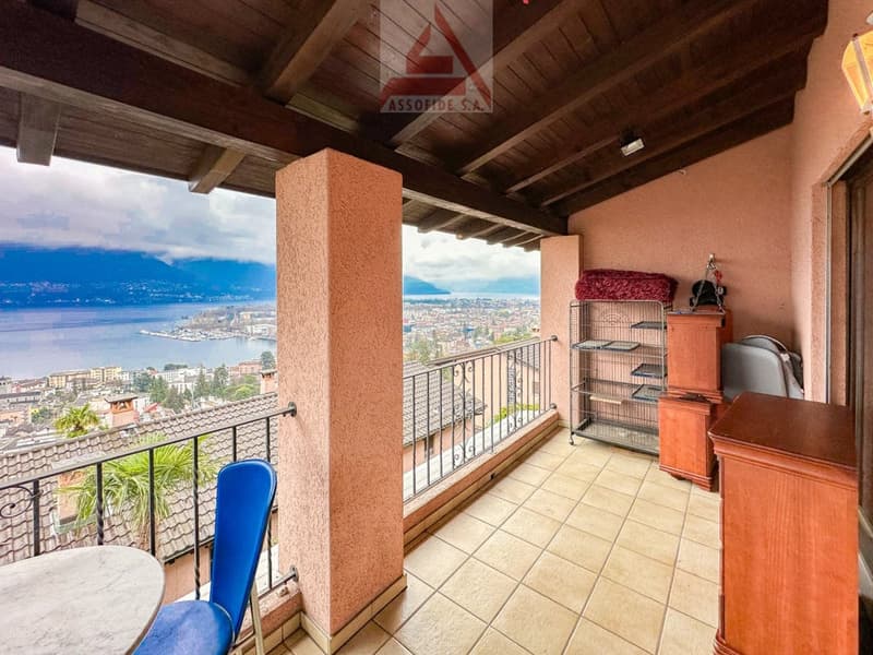 A large balcony with a view over the city, a table, and a chair.