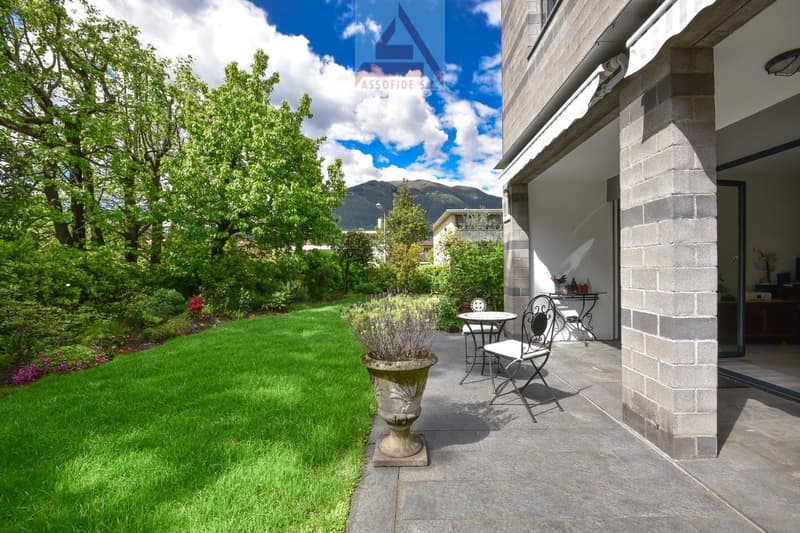 well-maintained garden, outdoor table and chairs, plants, greenery, pathway, house entrance, mountains in the background