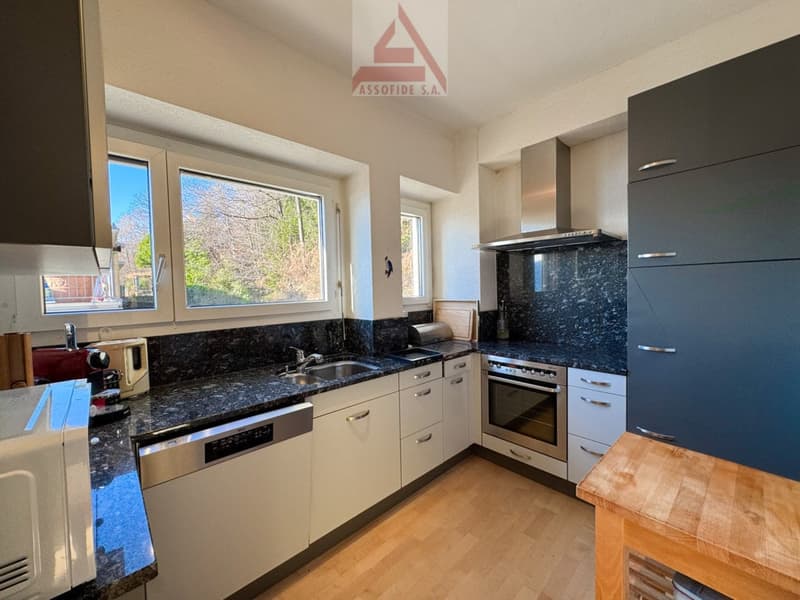 modern kitchen with granite countertops, white cabinets, integrated appliances, stainless steel fixtures