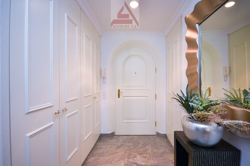 Tiled floor, white walls, arched door, silver planter, mirror, modern design, large hallway