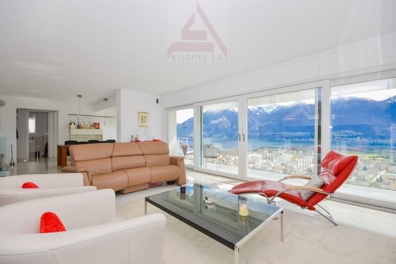 white tiles, glass sliding doors, large windows, beige sofa, two white armchairs, red chair, coffee table, carpet