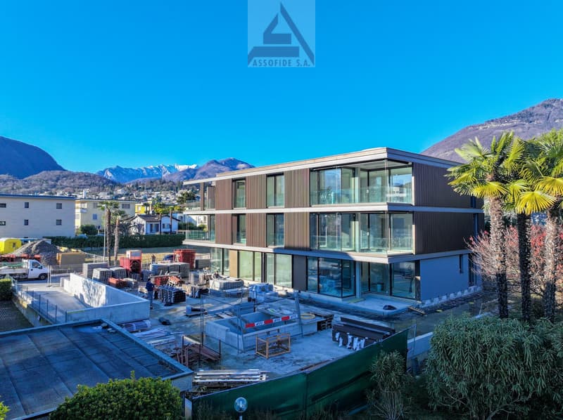Under construction modern house, brown facade, glass windows, mountains in background