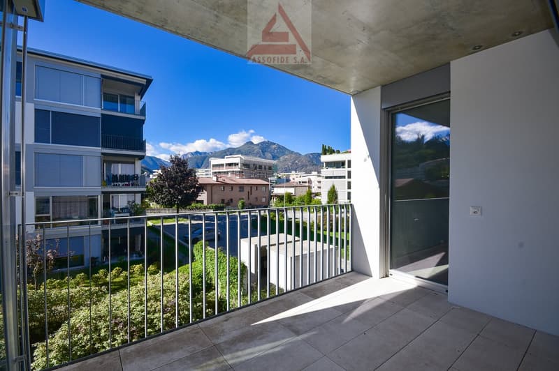 Outdoor balcony with metal railings, tiled floor, and views of the surrounding area