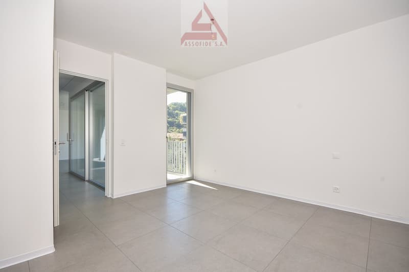 empty room with sliding glass doors, white walls, tiled floor, visible balcony