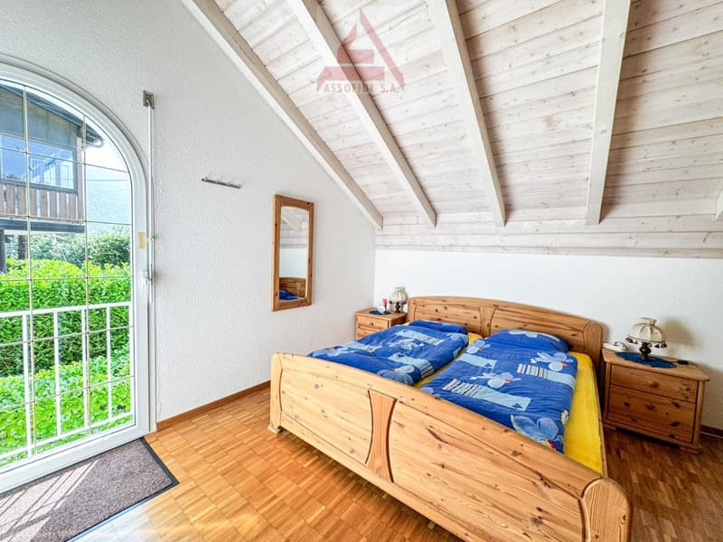 Bedroom with wooden bed, bedside tables, lamp, mirror, and sliding glass door.