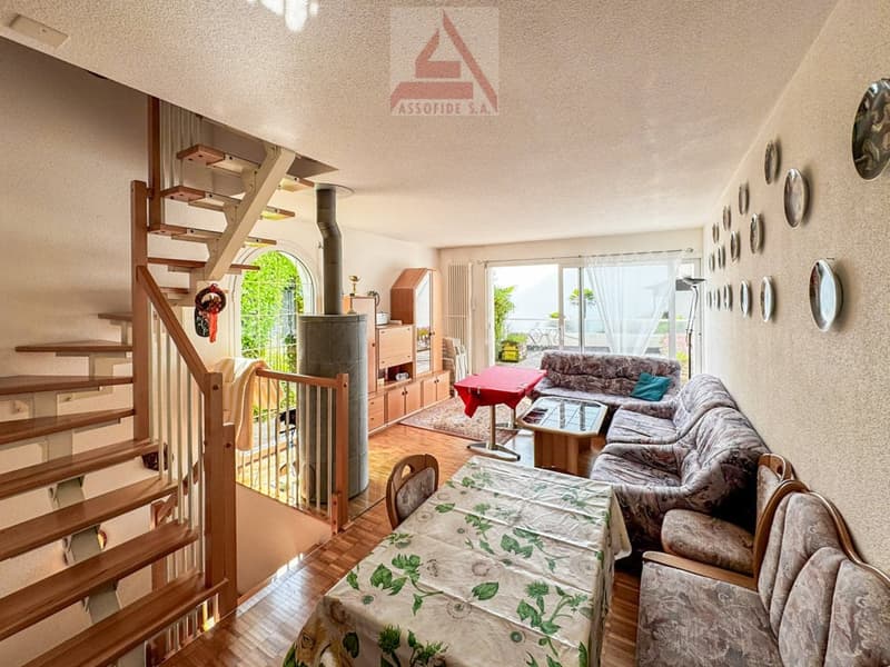 living room, dining table, floral table cover, sofa, armchairs, large windows, wooden stairs, radiator, fireplace, wooden floor, wooden cabinets