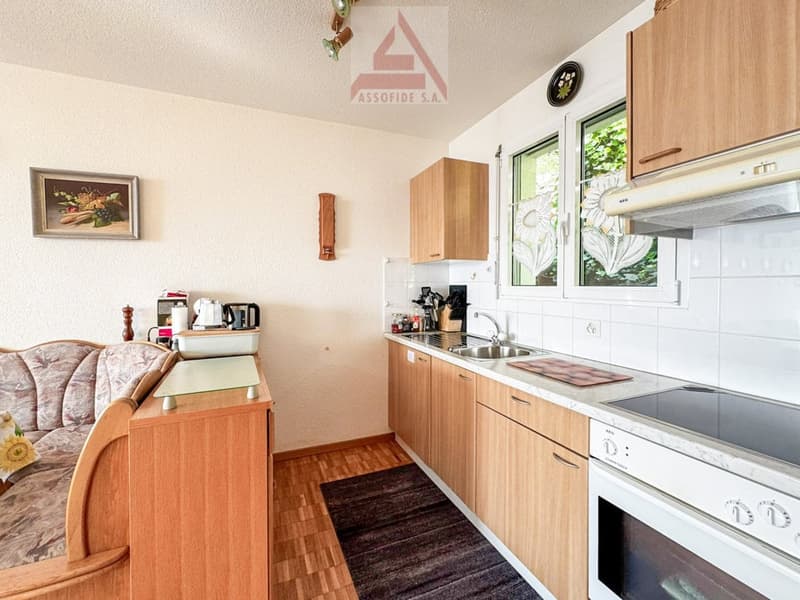 Modern kitchen with white countertops, wooden cabinets, an electric stove, oven, sink, and a coffee machine.