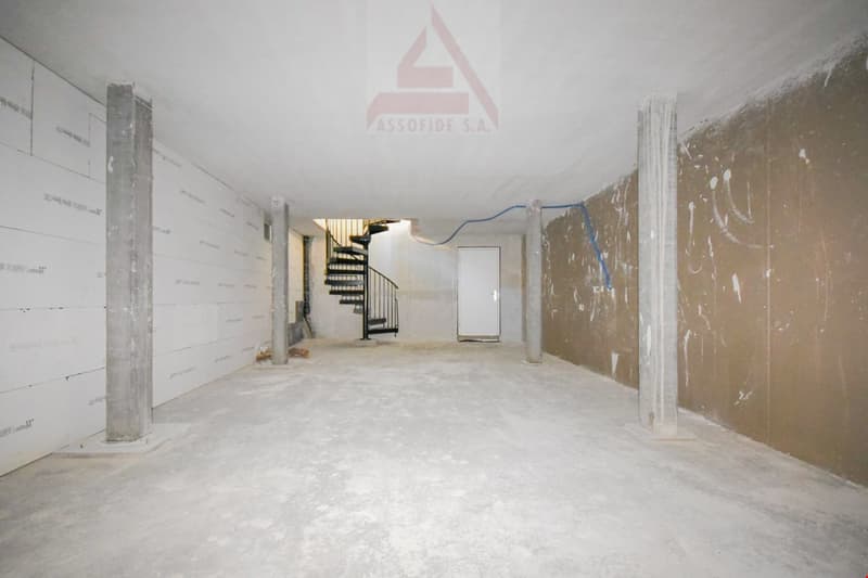large room with concrete floor, spiral staircase, and concrete pillars