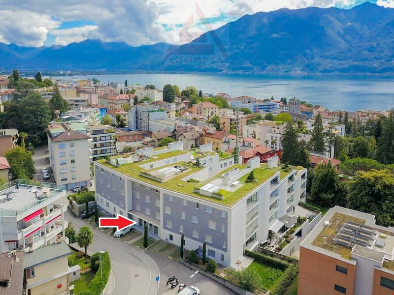 Building with green roofs, overlooking a lake and mountains, positioned in a city with a mountain view