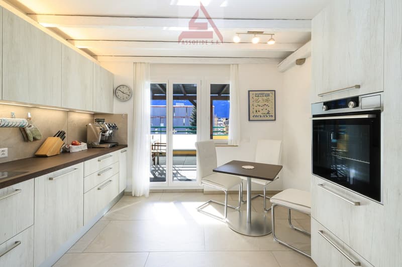 Modern kitchen with a breakfast table and chairs, white cabinets, brown countertop, glass doors to the balcony with a view