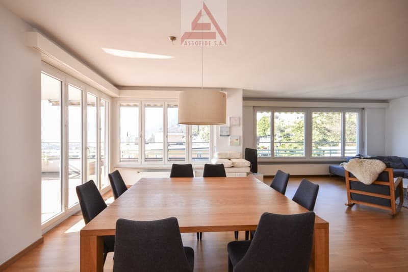 wooden dining table, 6 chairs, large windows, beige couch, wooden floor