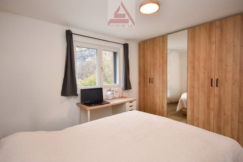 bedroom with a double bed, desk with laptop, curtains, wardrobe, view to the outside