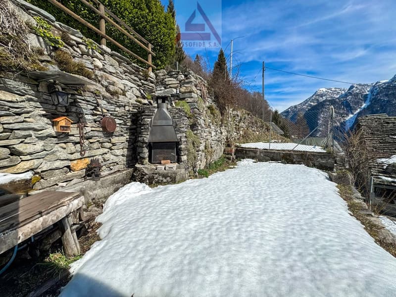 Stone wall, fireplace, wooden bench, snow, mountains in the background