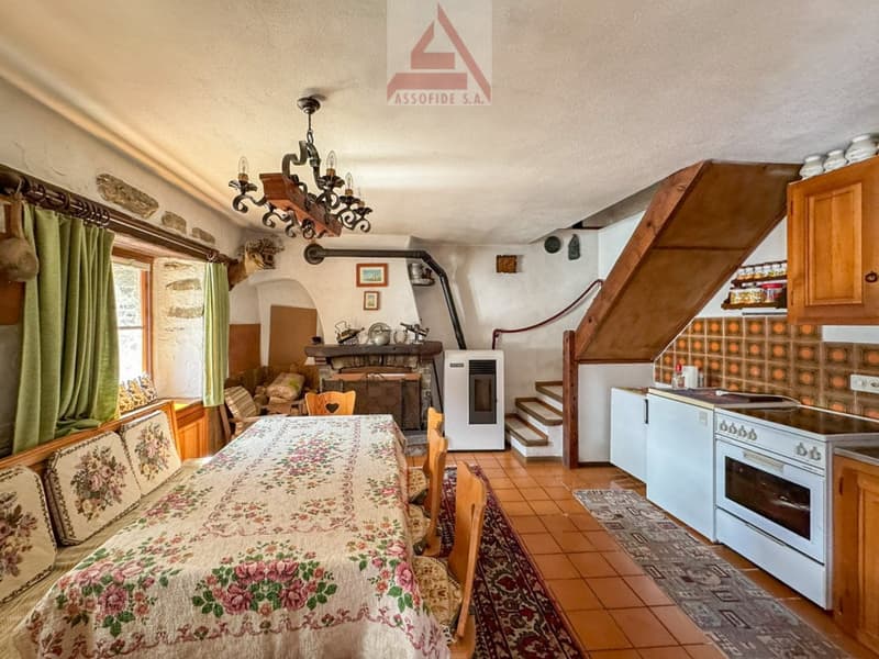 Dining room with a table, chairs, fireplace, kitchen, and a staircase