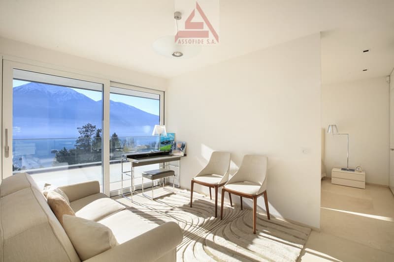 modern living room with large windows, balcony, desk, chairs, couch, rug, lamps
