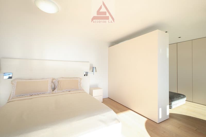 modern bedroom with a bed, nightstands, wall lamps, and a large white wardrobe