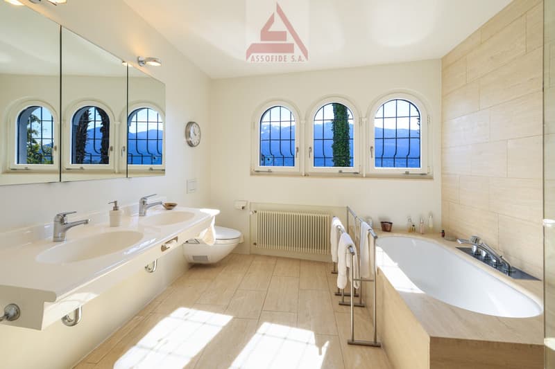 modern bathroom with double sink, bathtub, toilet, radiator, large windows, wooden floor